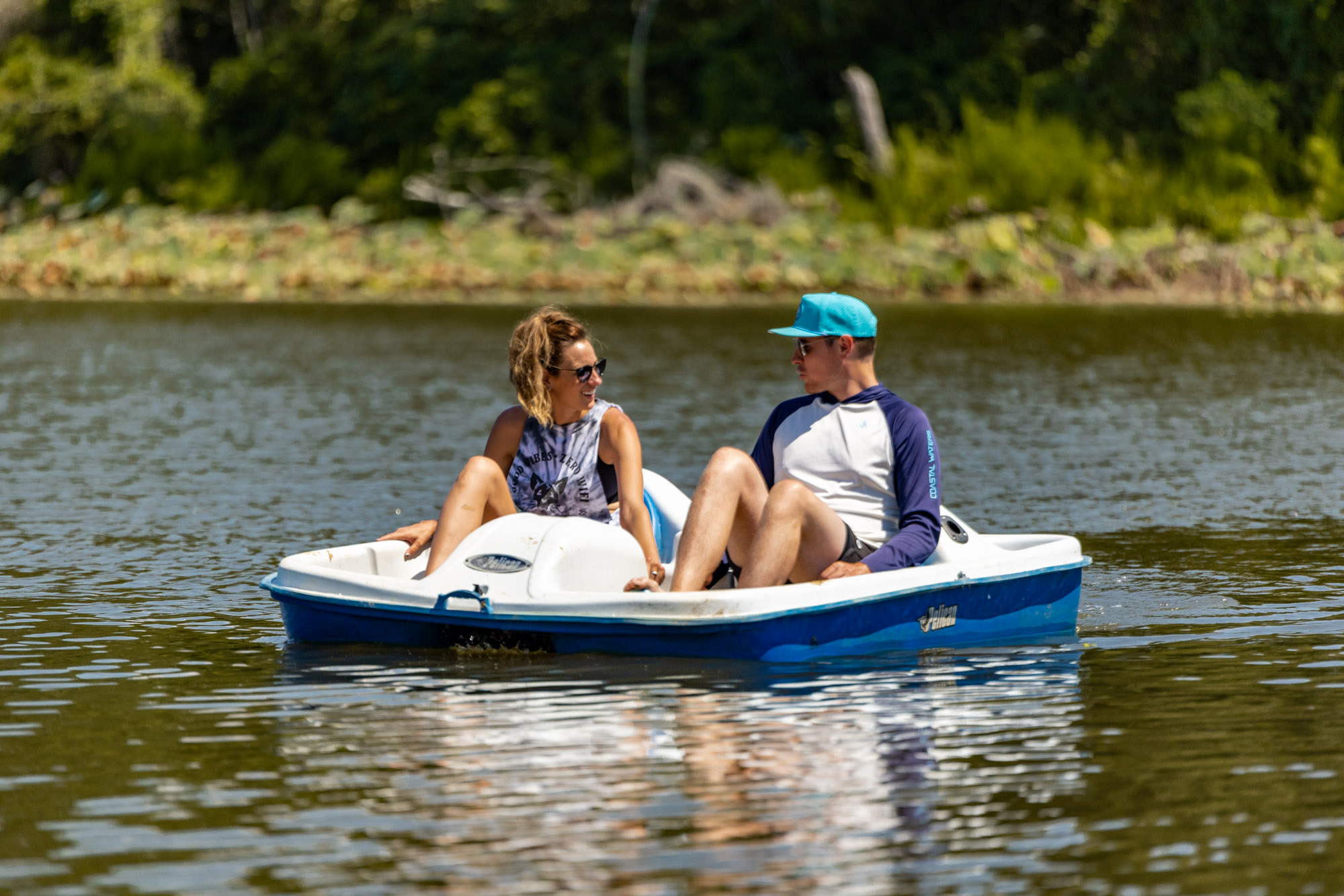 Man and woman riding in a pedal boat on a lake.